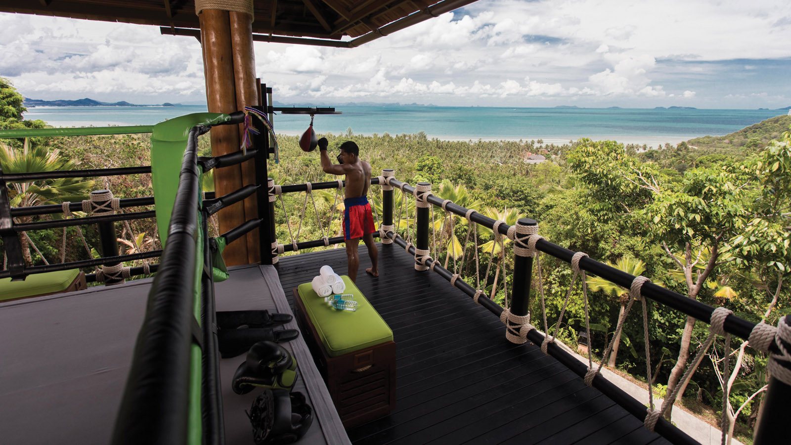 A Muay Thai athlete trains in the open-air ring at Four Seasons Resort Koh Samui, overlooking tropical forest and the Gulf.